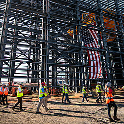 Foto: Aurubis: Gerüst einer Halle die sich gerade in Konstruktion befindet, die USA Flagge und Menschen sind auf der Baustelle zu sehen