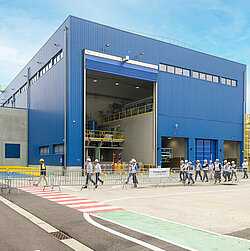 Foto: Aurubis: Eine blaue Halle von außen, das Tor ist auf