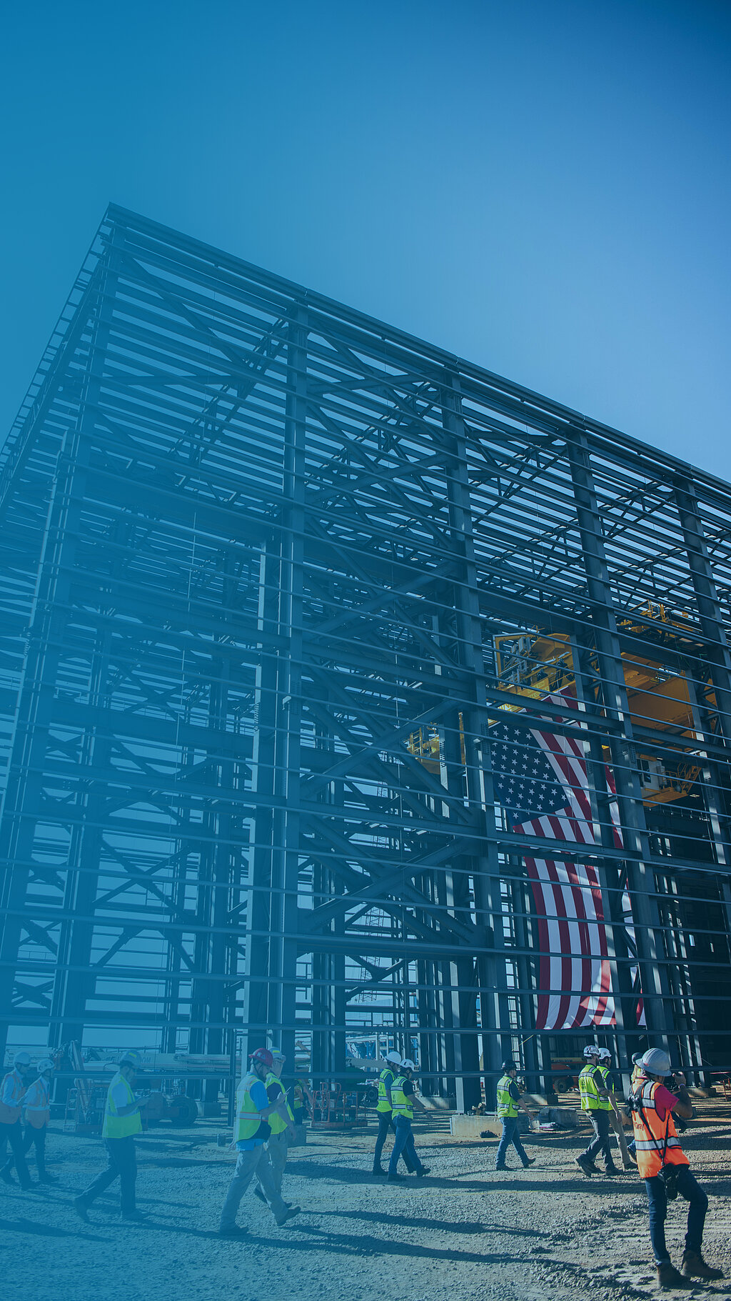 Foto: Aurubis: Gerüst einer Halle die sich gerade in Konstruktion befindet, die USA Flagge und Menschen sind auf der Baustelle zu sehen