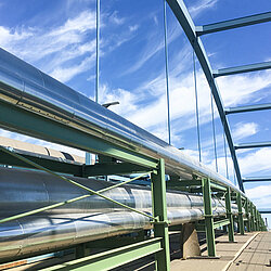 Foto: Aurubis: Mehrere lange Industrie Rohre auf einem gruenen Gestell