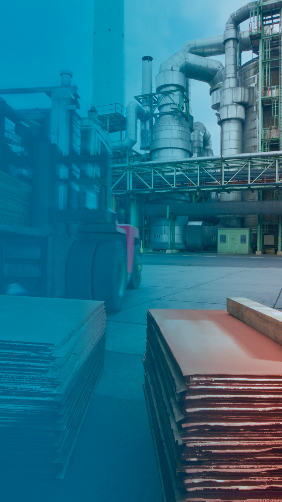 Foto: Aurubis: Bagger hebt Kupferplatten draußen, im Hintergrund ist das Werk zu sehen